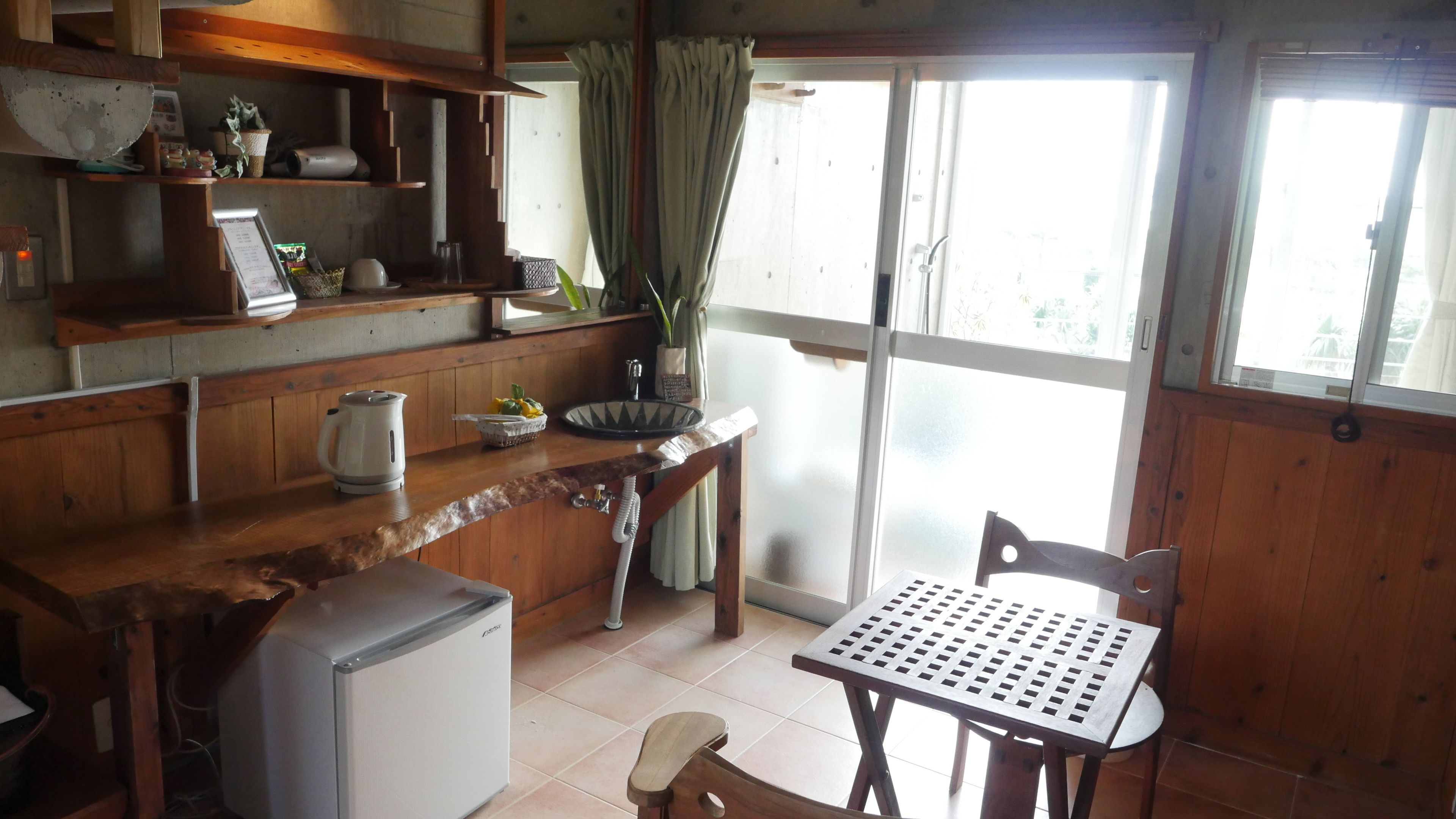A kitchen with wooden cabinets, a refrigerator, a sink, and a window with curtains.