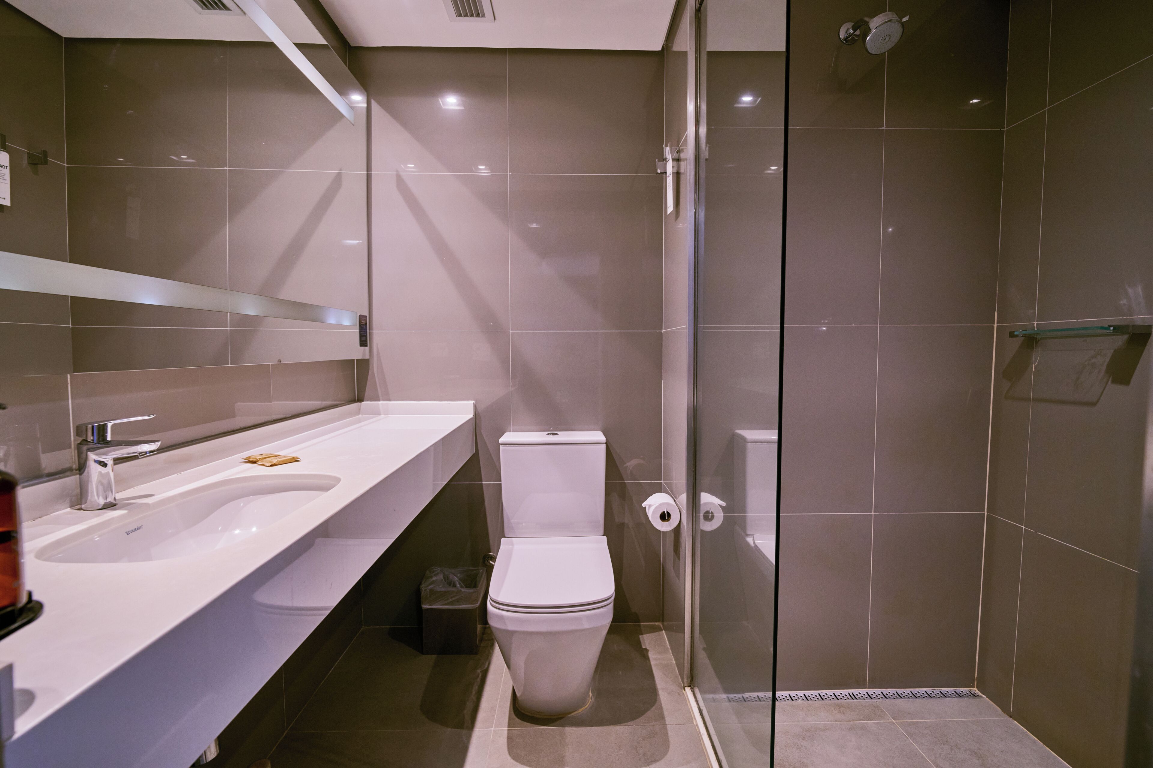Ein modernes Badezimmer mit einer Duschkabine aus Glas, einem weißen Waschbecken und einer Toilette.