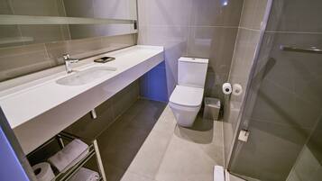 A modern bathroom with a white sink, a toilet, and a glass shower enclosure.