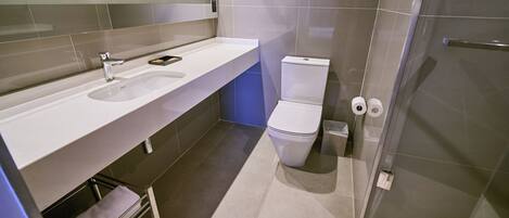 A modern bathroom with a white sink, a toilet, and a glass shower enclosure.