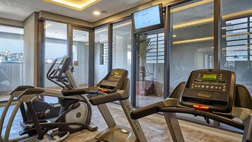 Un gimnasio con cintas de correr, una bicicleta estática y una pantalla de televisión.