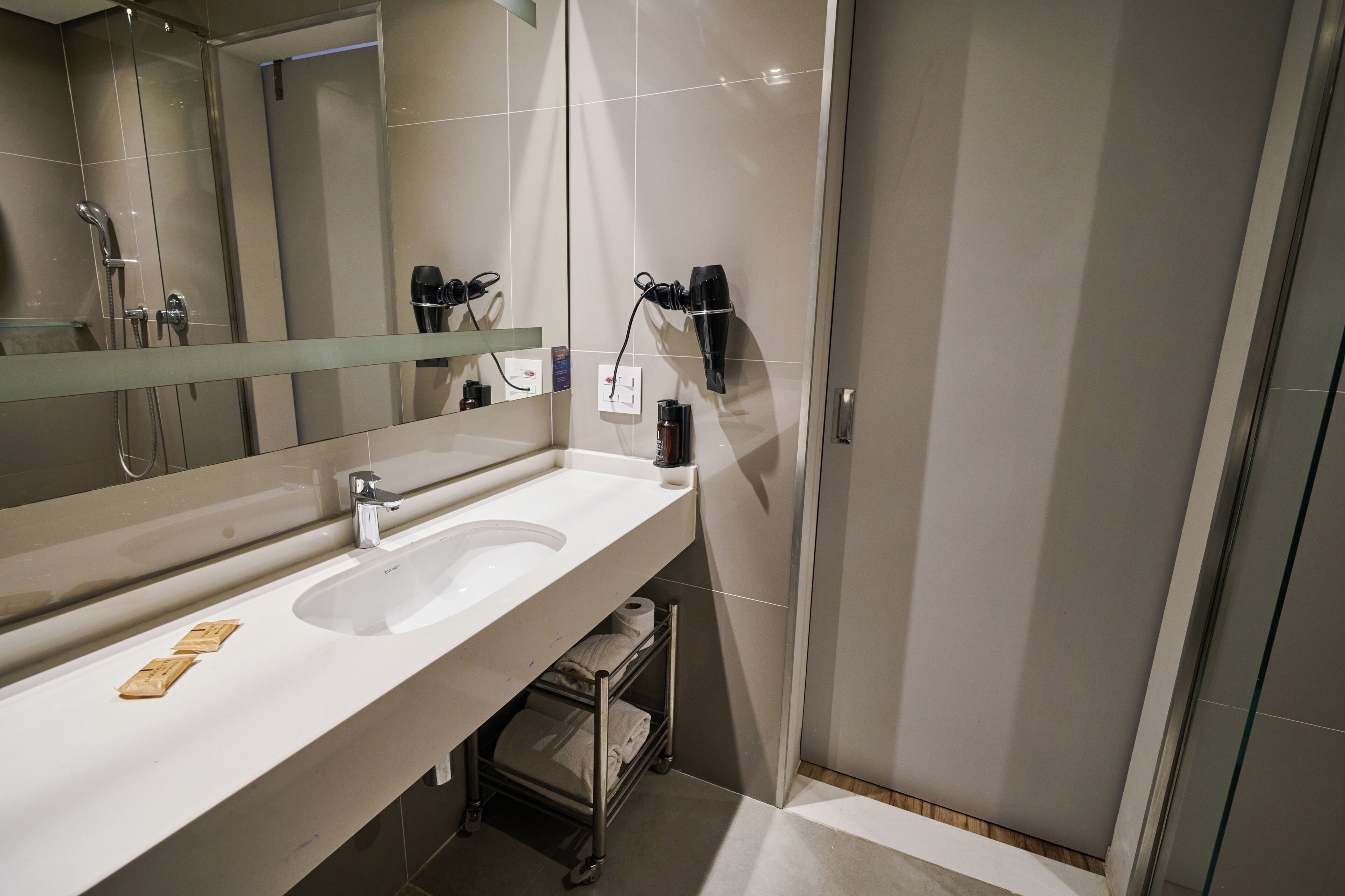 Une salle de bain moderne avec un grand miroir, un lavabo, une douche et un porte-serviettes.