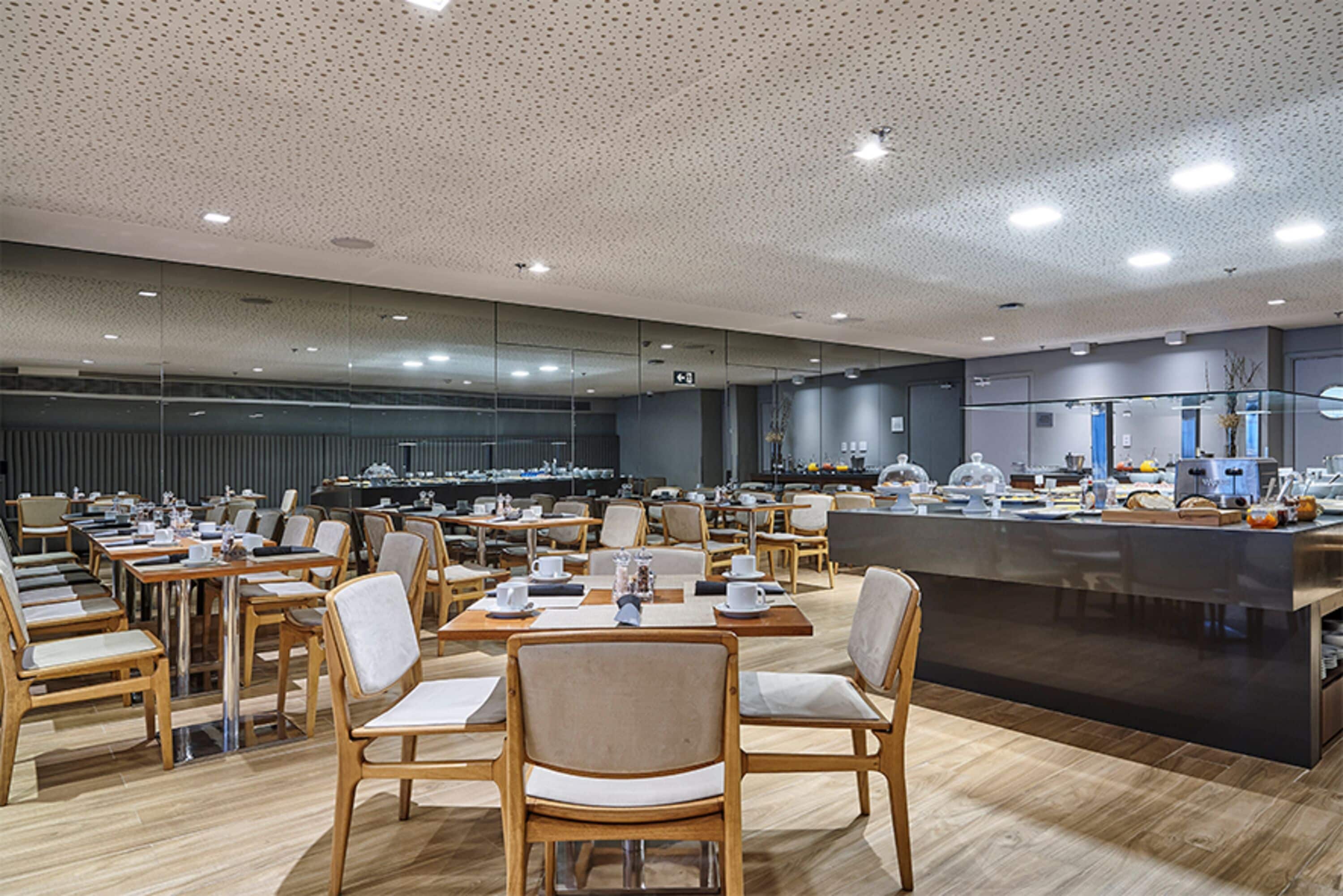 A spacious dining area with multiple tables and chairs, a central island with a counter, and a modern ceiling design.