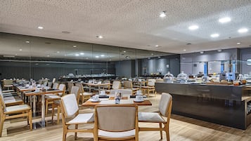 A spacious dining area with multiple tables and chairs, a central island with a counter, and a modern ceiling design.