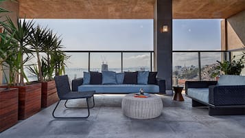 A modern outdoor seating area with a sofa, chairs, and a round ottoman.