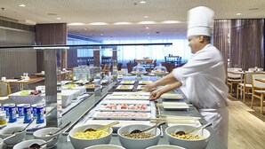 Een buffetopstelling met diverse gerechten en een kok die aan het koken is.