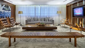 Een moderne woonkamer met een bank, twee fauteuils, een salontafel en een aan de muur bevestigde televisie.