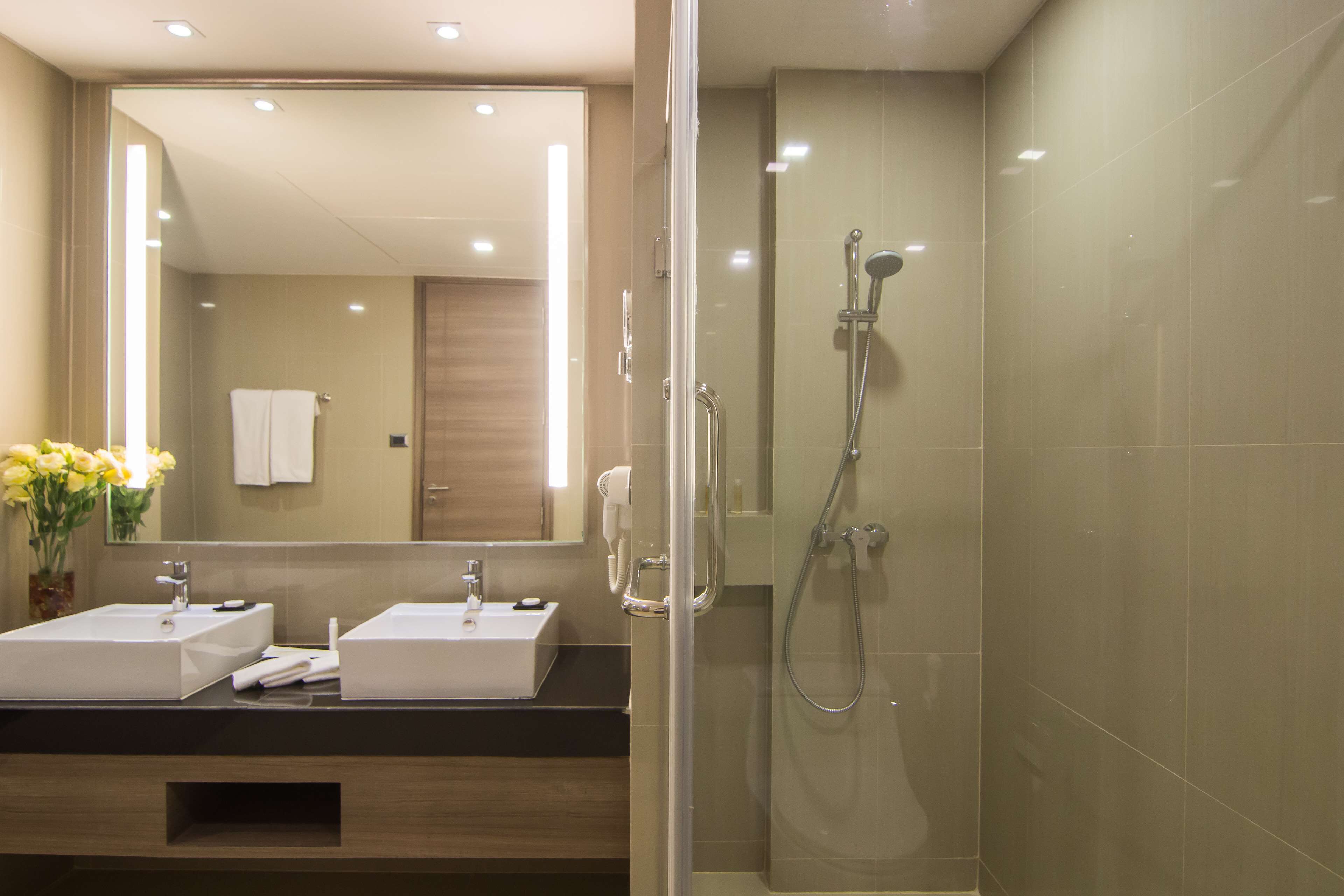 A modern bathroom with two sinks, a glass shower enclosure, and a large mirror.