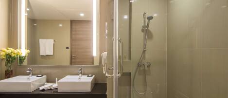 A modern bathroom with two sinks, a glass shower enclosure, and a large mirror.