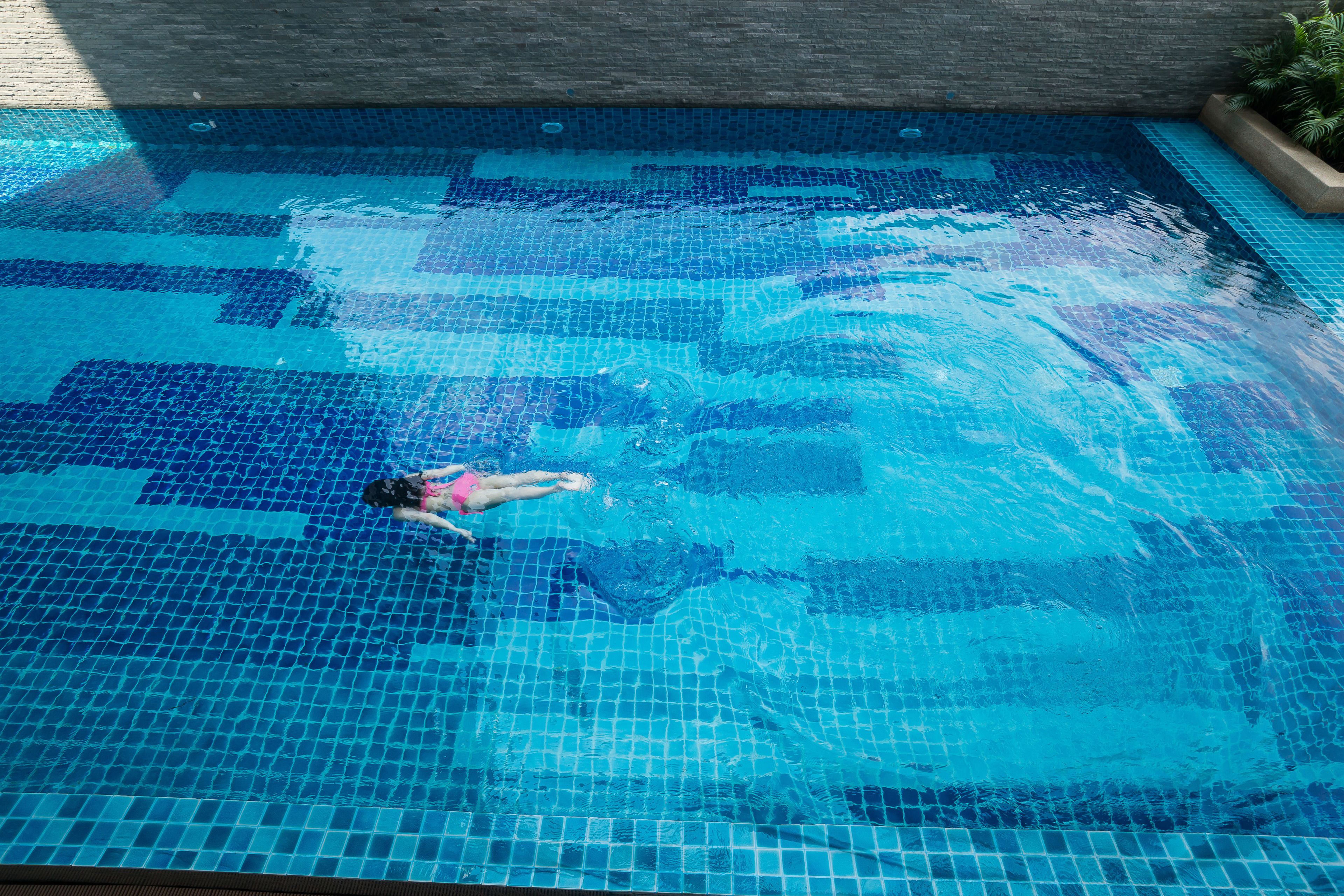 A swimming pool with a tiled floor and a person swimming.