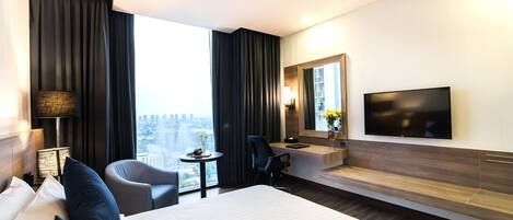 Een hotelkamer met een groot bed, een bureau, een stoel, een televisie en uitzicht op de stad.