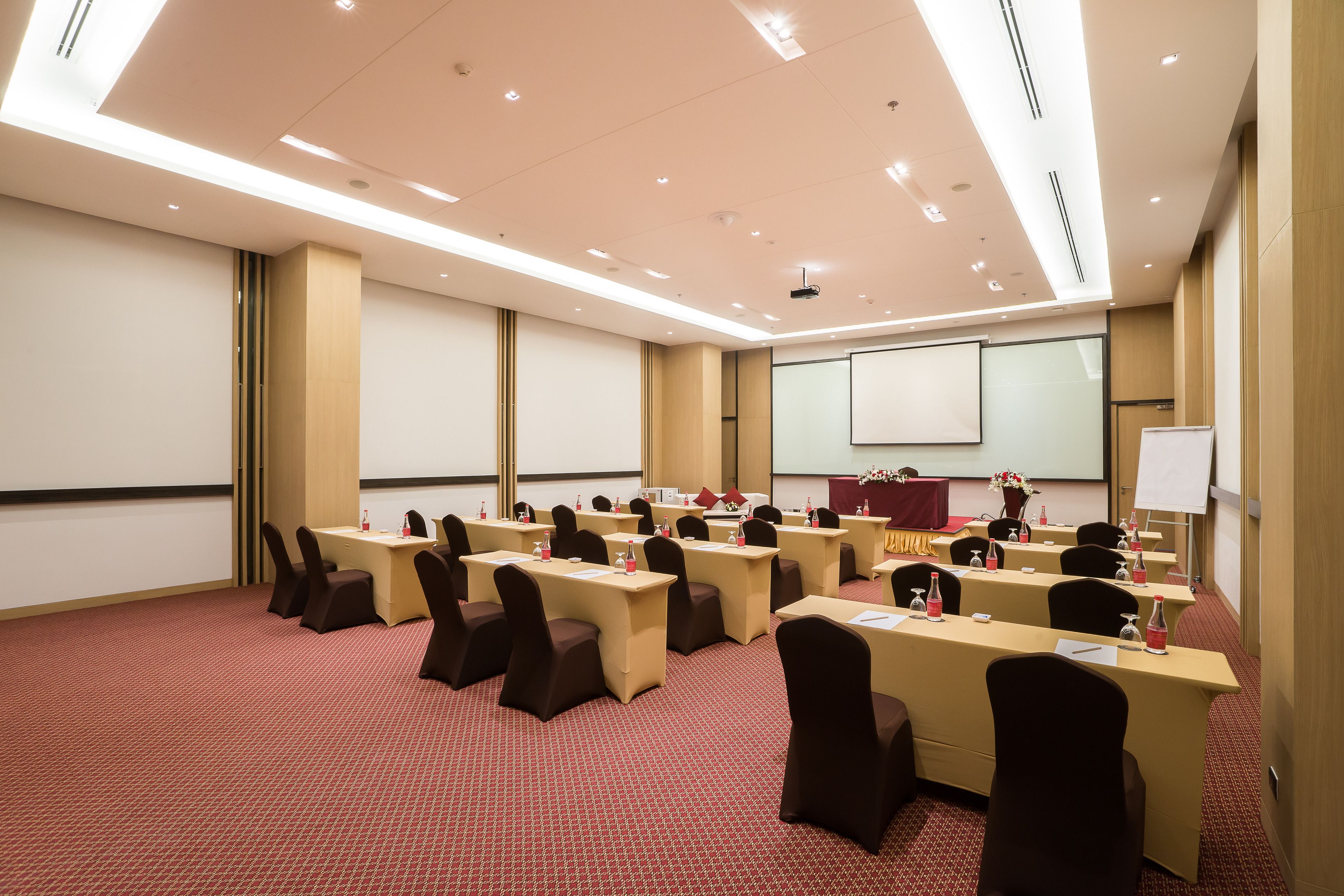 A conference room with multiple tables and chairs, a projector screen, and a whiteboard.
