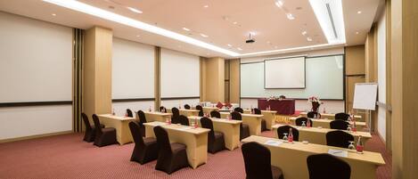 A conference room with multiple tables and chairs, a projector screen, and a whiteboard.