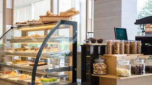 Vitrine de uma padaria com diversos produtos de panificação e potes de biscoitos.