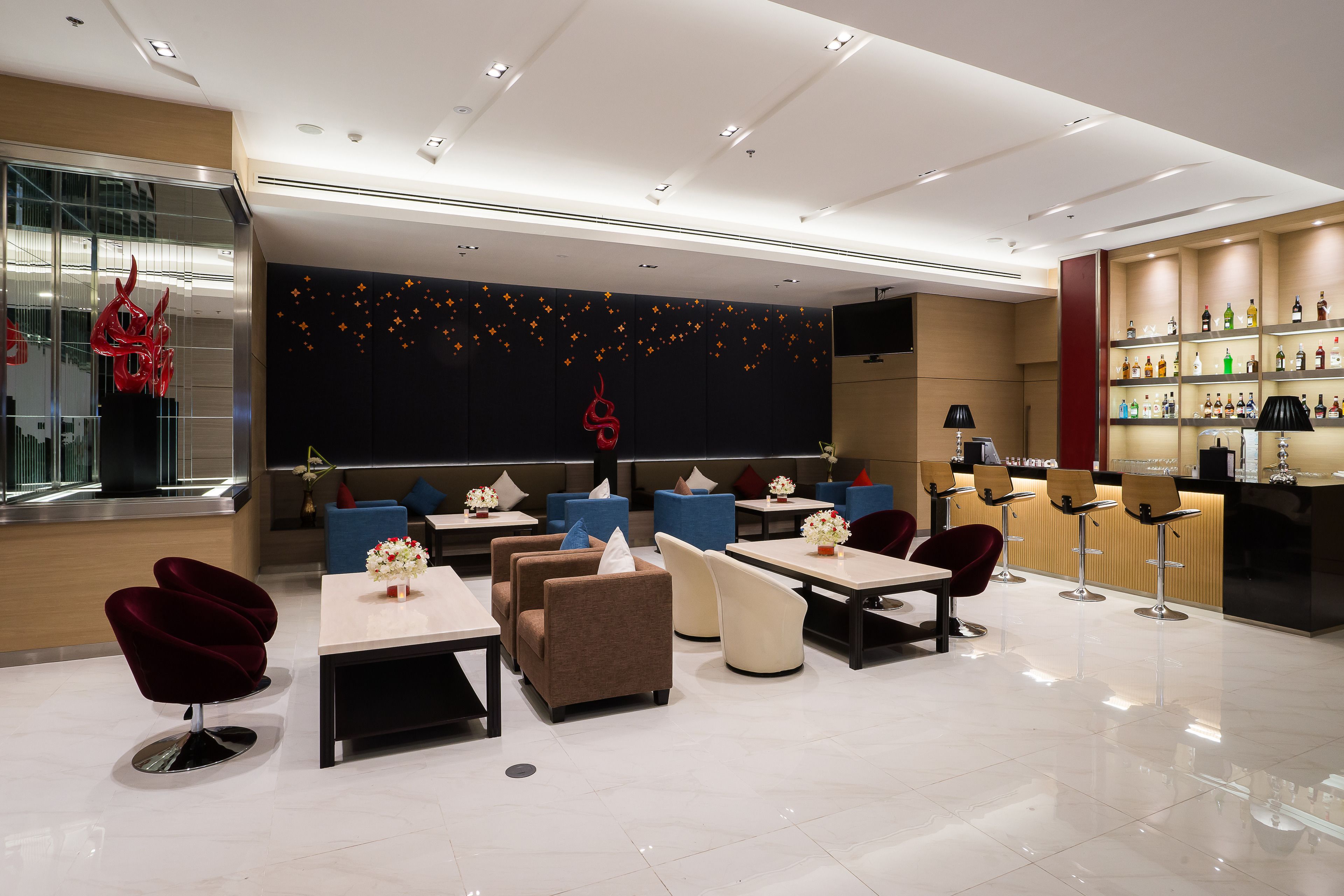A modern lounge area with seating, a bar, and a display of bottles.