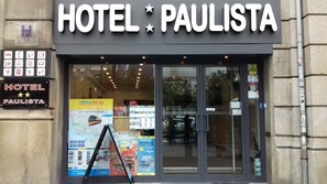 Fachada del Hotel Paulista con un cartel que muestra servicios y un mapa para visitas guiadas por la ciudad.