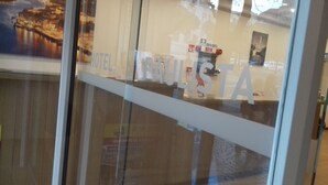 Interior de un hotel con una puerta de vidrio que refleja un paisaje urbano y un letrero que dice 'HOTEL'.