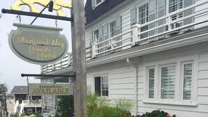 A hotel named "Marginal Way House Hotel" with a signboard, a stone wall with flowers, and a white building with windows and a balcony.