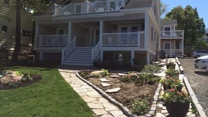 A two-story house with a front porch, a balcony on the second floor, and a stone pathway leading to the entrance.