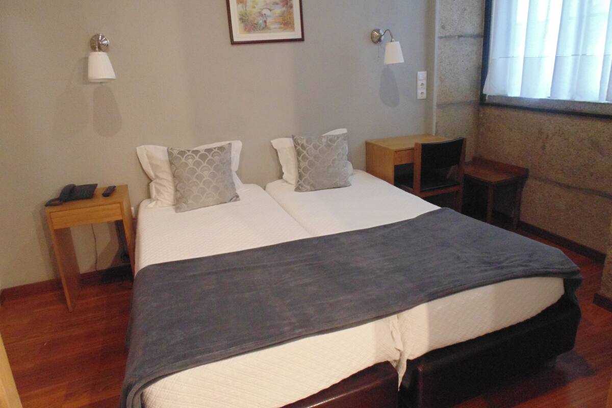 A hotel room with a large bed, two bedside tables, a nightstand, a lamp, and a painting on the wall.