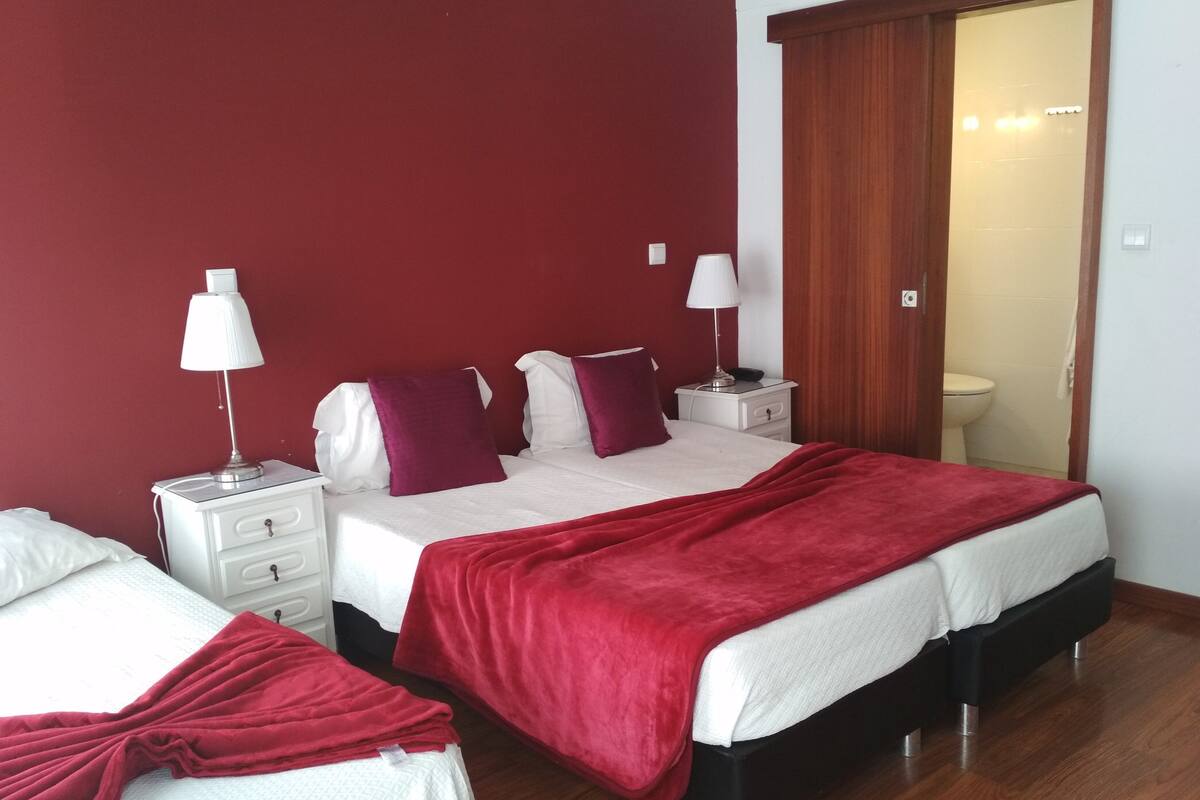 A hotel room with a large bed, two bedside tables, and a wardrobe.