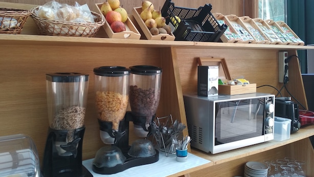 A kitchen area with a microwave, coffee makers, and a fruit display. - Hotel Porto Rico (Porto)