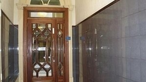 A hallway with a wooden door with glass panels and a tiled wall. - Hotel Porto Rico (Porto)
