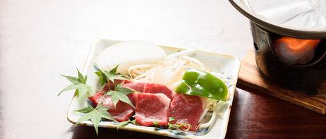 A dish with raw meat, vegetables, and noodles on a ceramic plate.