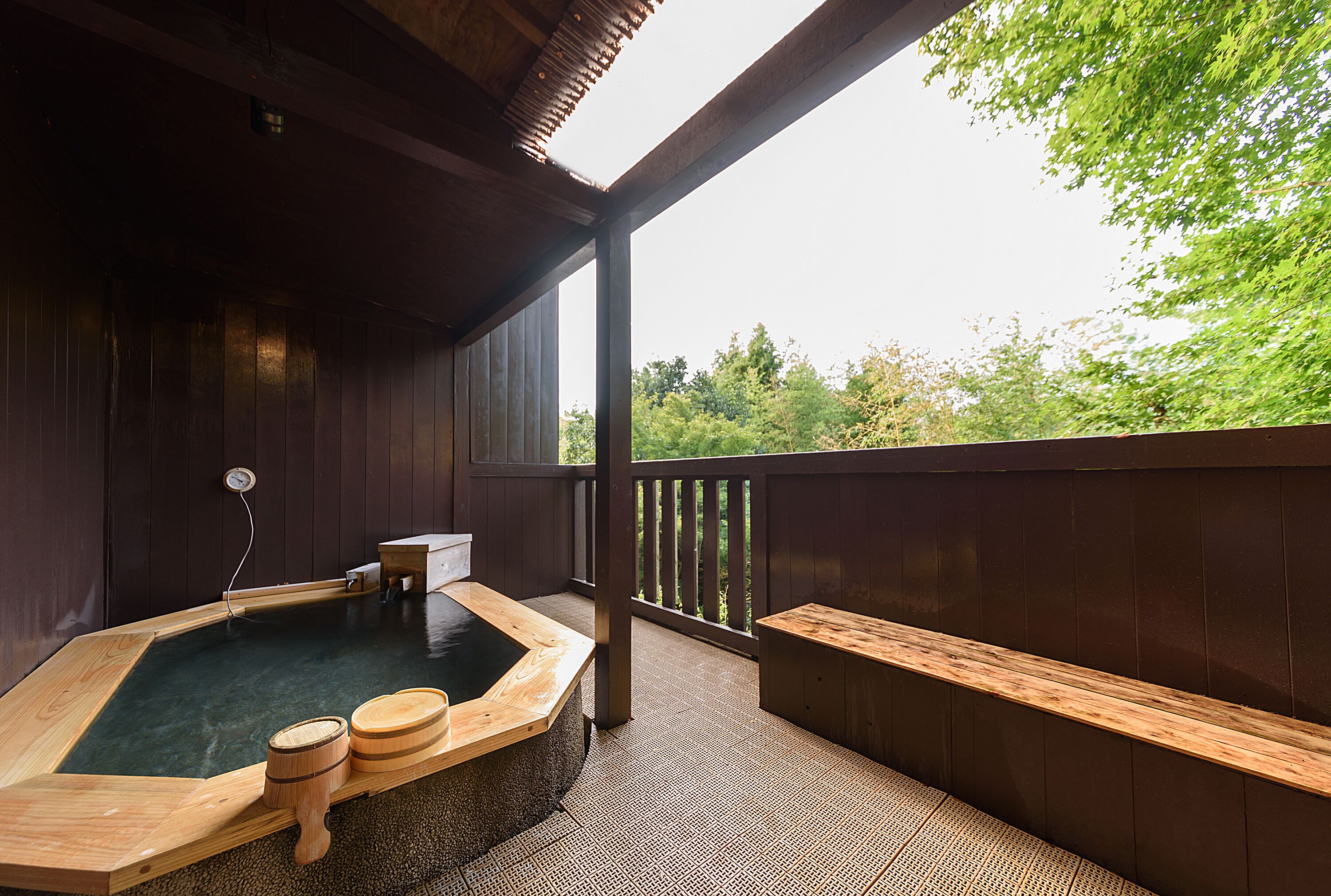 A hot spring bath area with wooden benches and a wooden platform.
