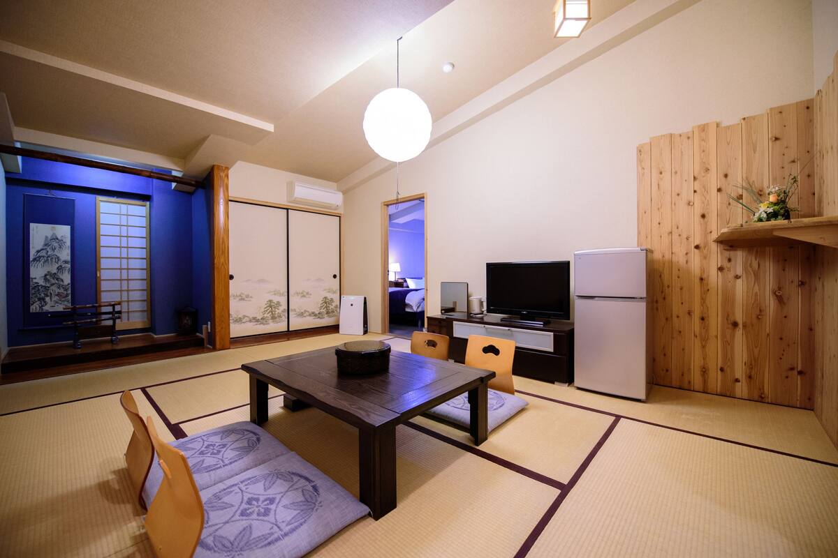 A traditional Japanese-style living room with tatami flooring, a low table, and a television.