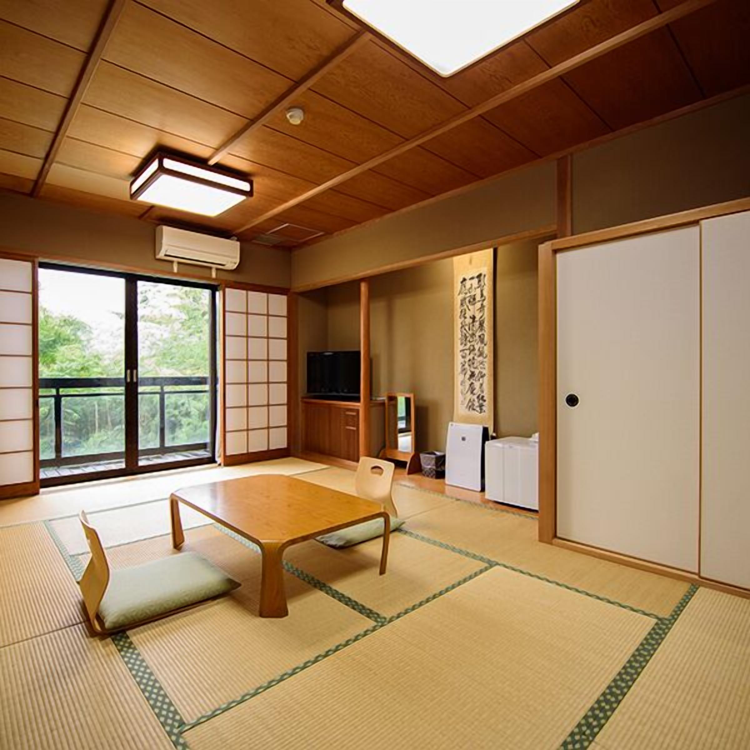 Um quarto japonês tradicional com tatames, uma mesa baixa, portas deslizantes e uma televisão.
