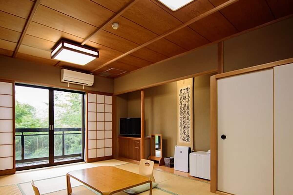Ett traditionellt japanskt rum med tatamimattor på golvet, ett lågt bord, skjutdörrar och en tv.