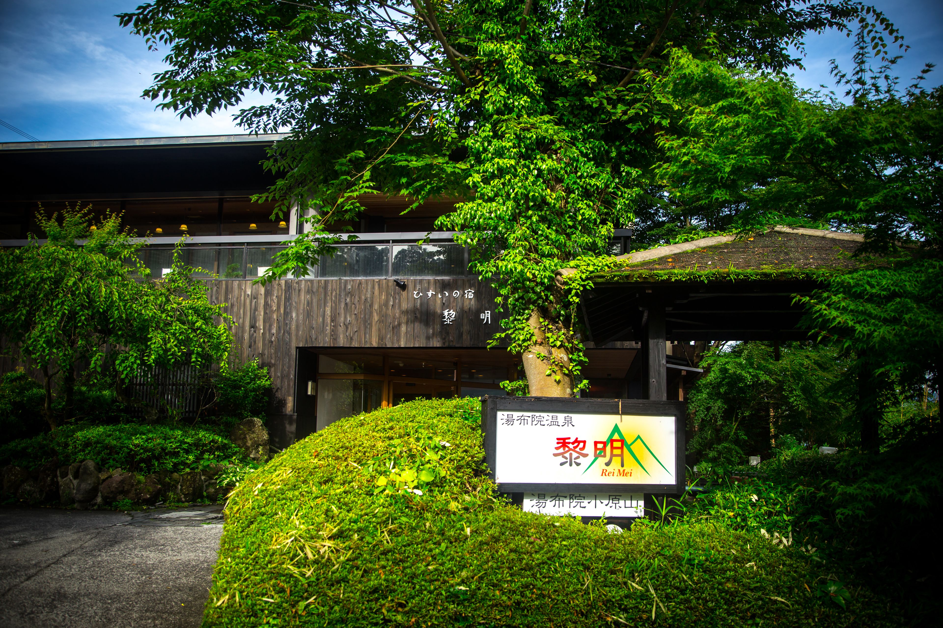 A building with a signboard, surrounded by greenery and trees.