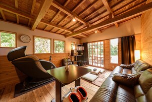 Un interior de madera con una silla de masaje, un sofá, una mesa y una estantería.