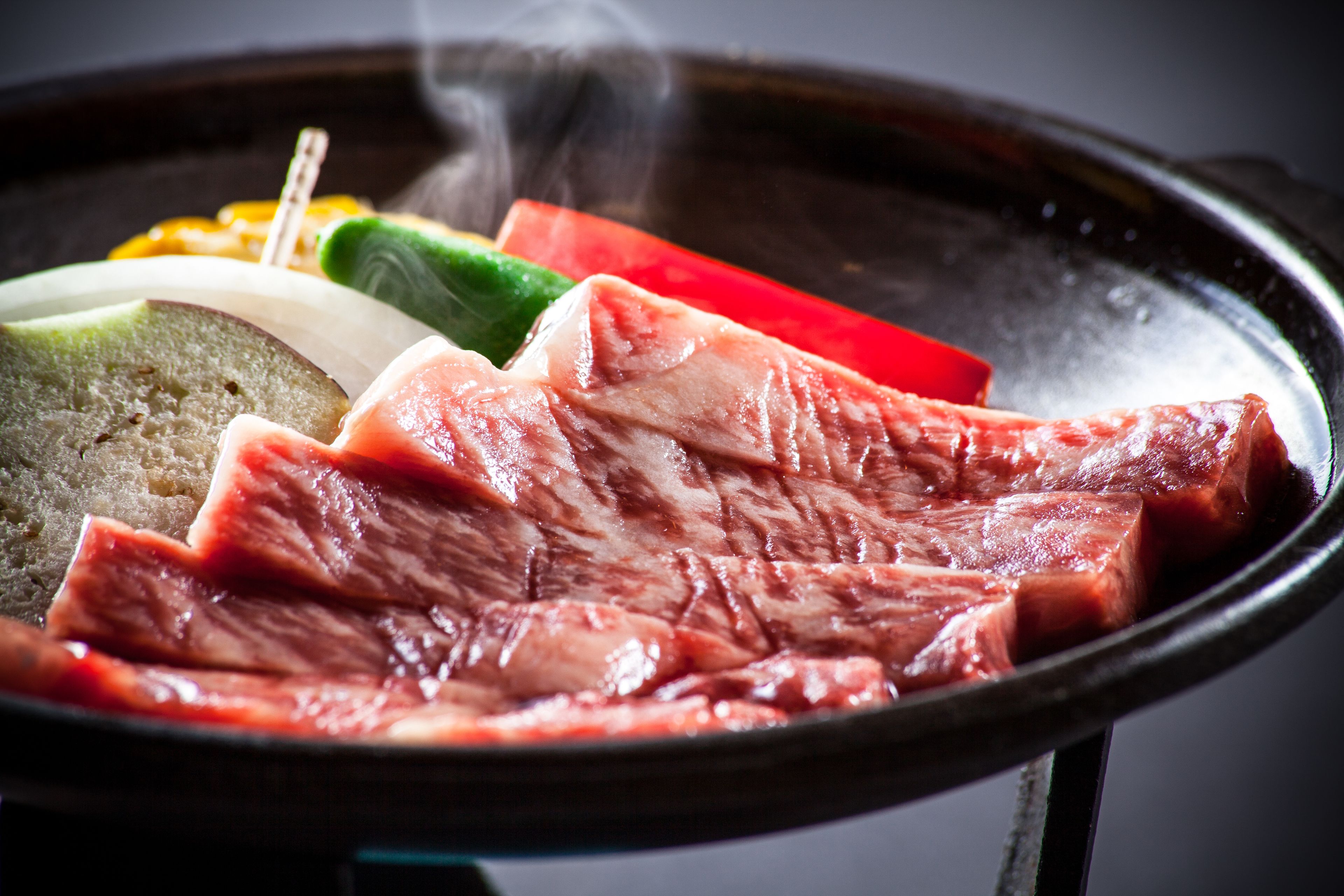 Ein Detailaufnahme von rohem Fleisch und Gemüse auf einem Grill.