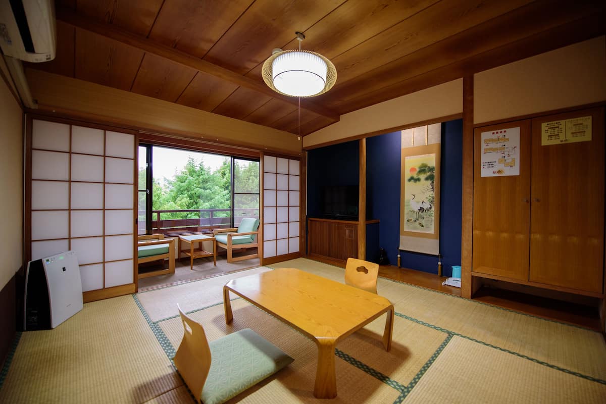 A traditional Japanese room with tatami flooring, a wooden table, and sliding doors.