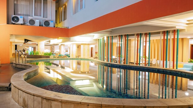 A hotel interior with a central swimming pool, multiple balconies, and indoor seating areas. - Siesta Legian Hotel (Legian)