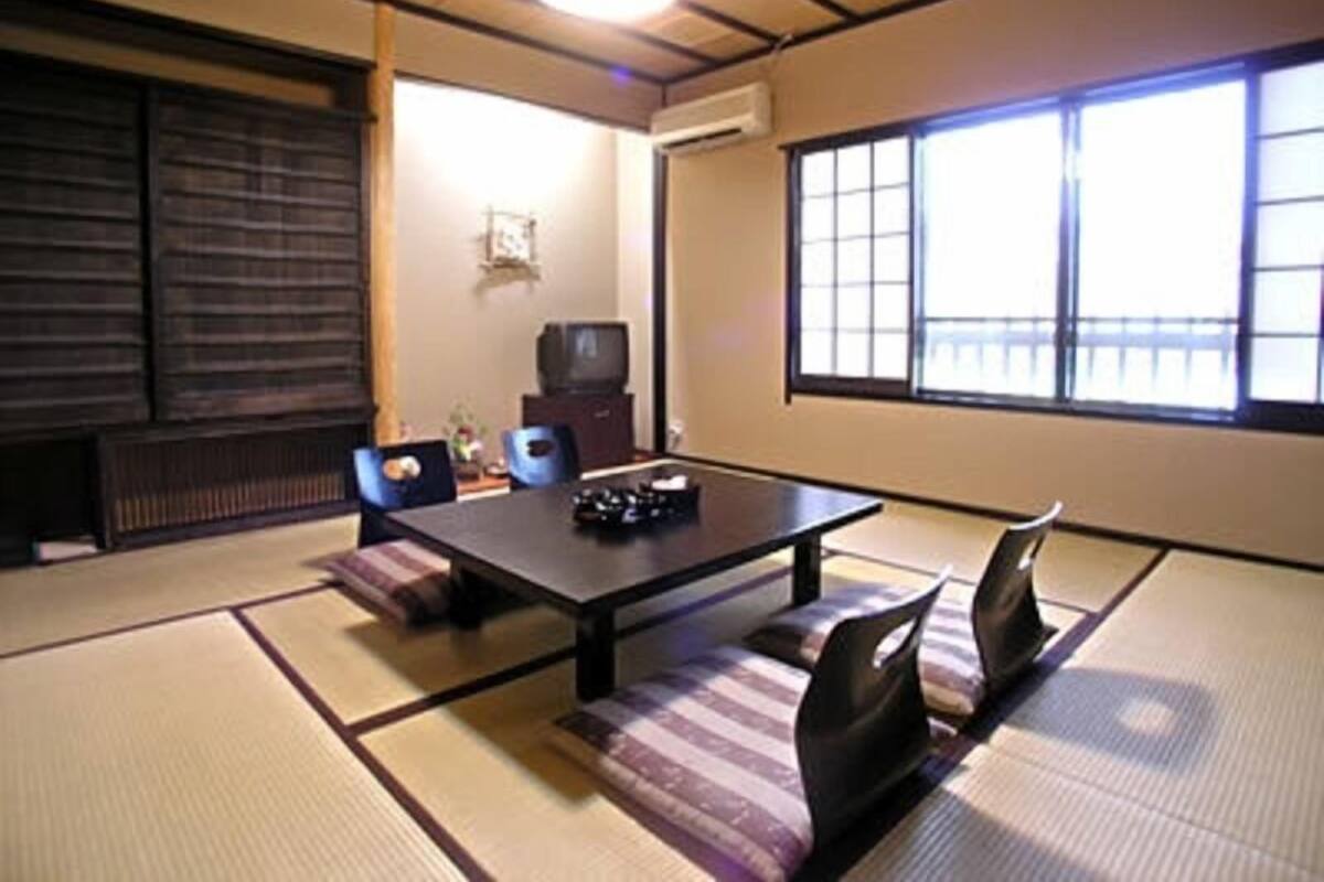 A traditional Japanese-style room with tatami flooring, a low table, and cushions.