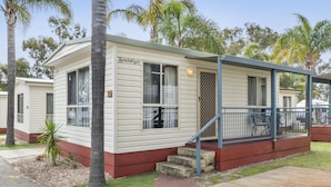 A mobile home with a porch, steps, and a small garden area. - Central Caravan Park (Ascot)