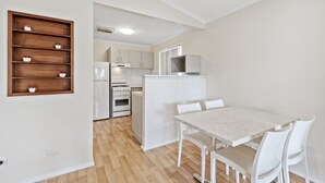A modern kitchen with white cabinets, a built-in oven, and a microwave. - Central Caravan Park (Ascot)