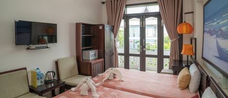 Habitación de hotel con dos camas, televisión, armario y ventana con cortinas.
