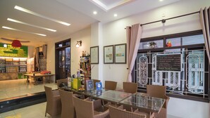 A hotel dining area with a glass-top table surrounded by wicker chairs, a small bar area with bottles, and framed certificates on the wall. - The House 36 (Da Nang)