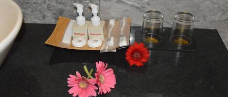 A bathroom counter with toiletries, including bottles of shampoo and bath gel, and two small containers with yellowish contents.
