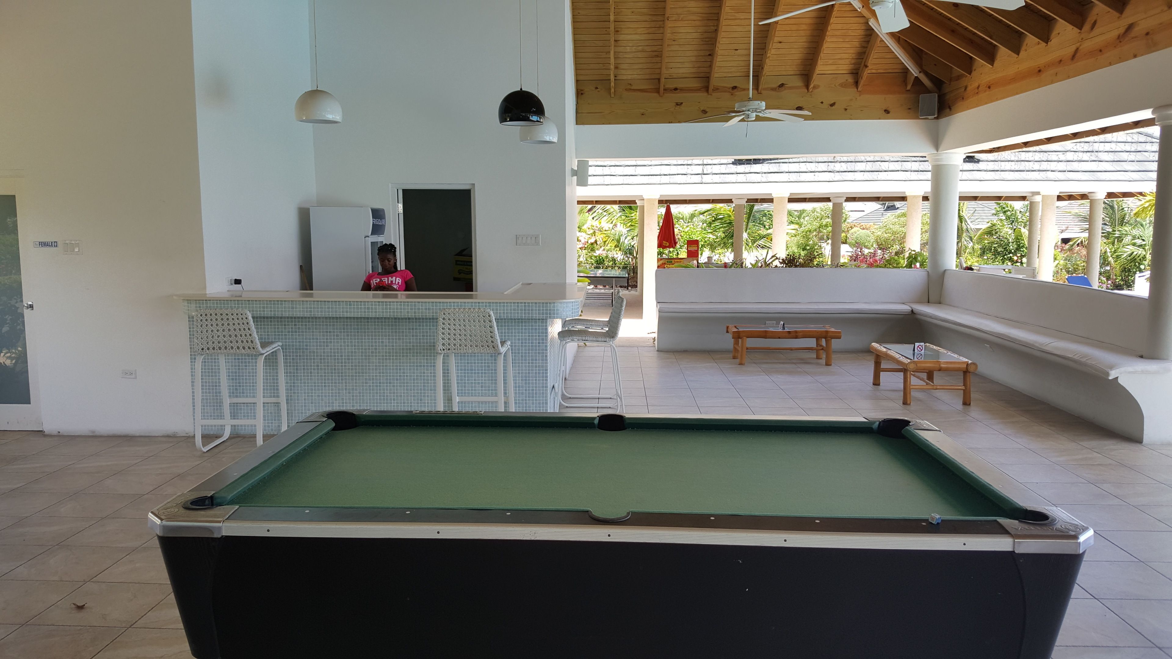 Una mesa de billar en un espacio cubierto con un bar y asientos.