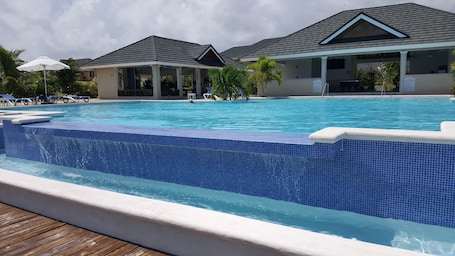 Una piscina al aire libre, sombrillas, sillones reclinables de piscina