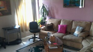 Un salon comprenant un canapé, une table basse, un fauteuil, une petite table et une plante en pot.