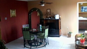 Un salon comprenant une table à manger, des chaises, une cheminée et un ventilateur de plafond.