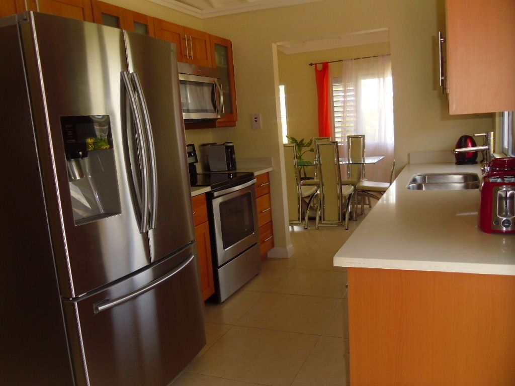 A kitchen with stainless steel appliances, wooden cabinets, and a dining area with a table and chairs.