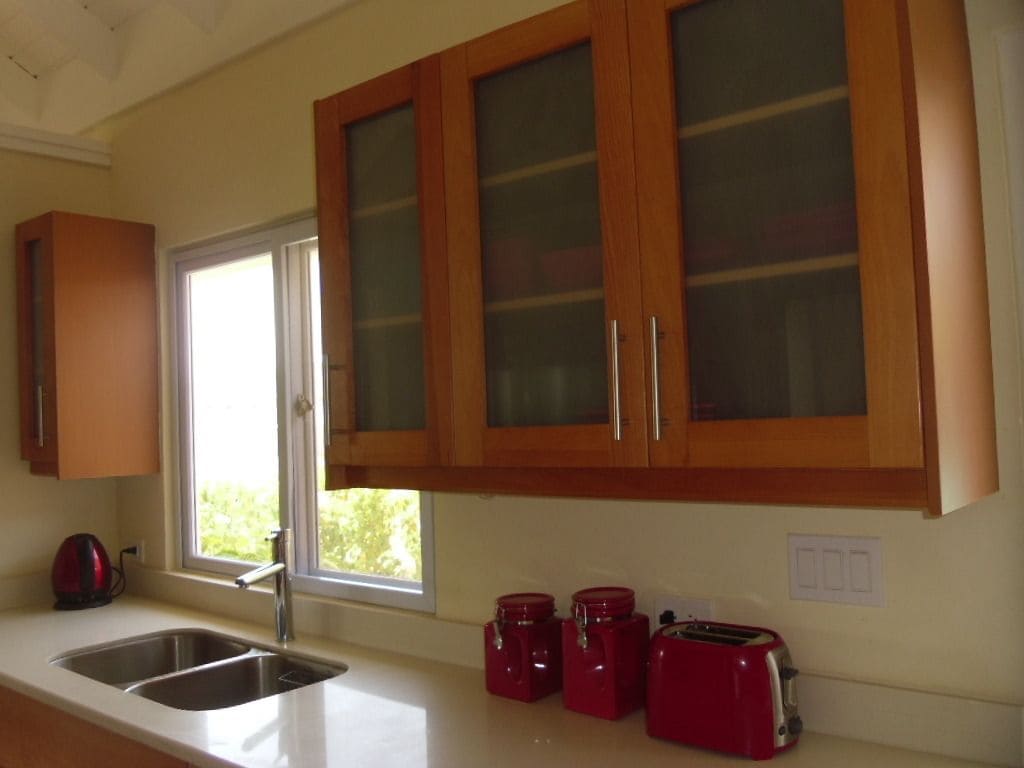 A kitchen with wooden cabinets, a stainless steel sink, a window, and red appliances.