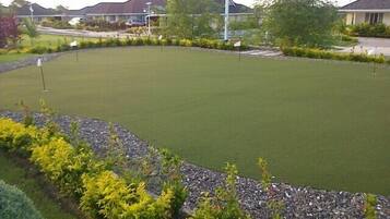 Enjoy a serene round of golf on this meticulously maintained course with a lush green surface and scenic gravel path.